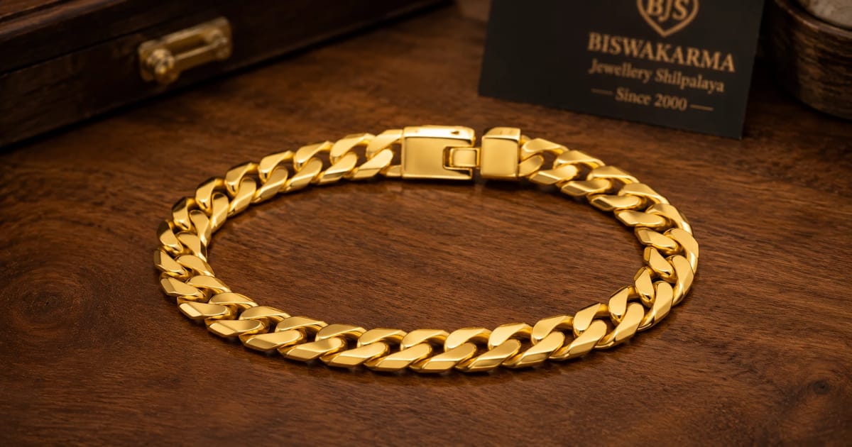 Gold mens bracelet in a flat curb link resting on a wooden counter