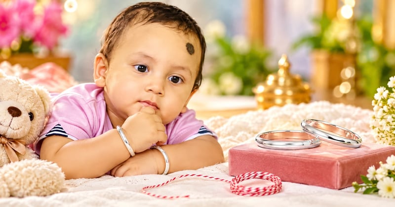 Plain solid kids silver bangle on a baby's wrist beside a thread used to measure the folded hand